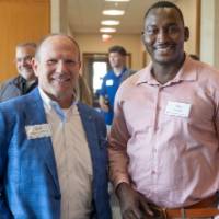 Two gentleman at event standing together and smiling for camera